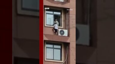 Child plays on high-rise window ledge in China. #Shorts #China #BBCNews